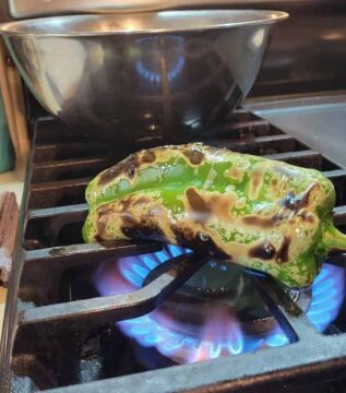 green chili being roasted over open gas flame, blistering