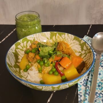 finished chicken curry in decorative bowl, mint chutney in mason jar