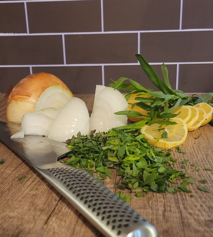 cutting board with knife, onion, lemon, and tarragon