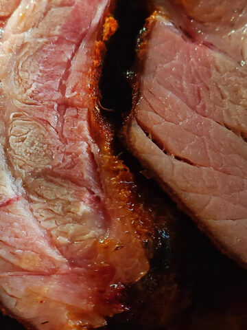 close up of finished ribs, cut to show outside crust, pink smoke ring, and juicy meat