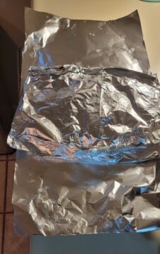 crimped foil packet of potatoes, on top of an additional length of foil