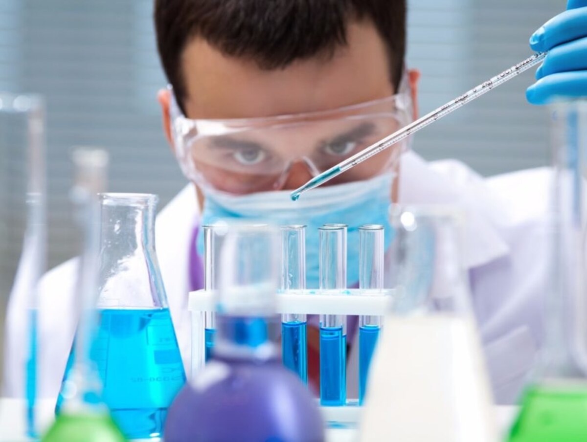 chemist in laboratory looking at test tubes