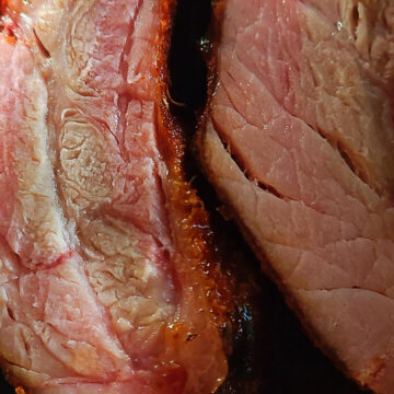 close up of finished ribs, cut to show outside crust, pink smoke ring, and juicy meat