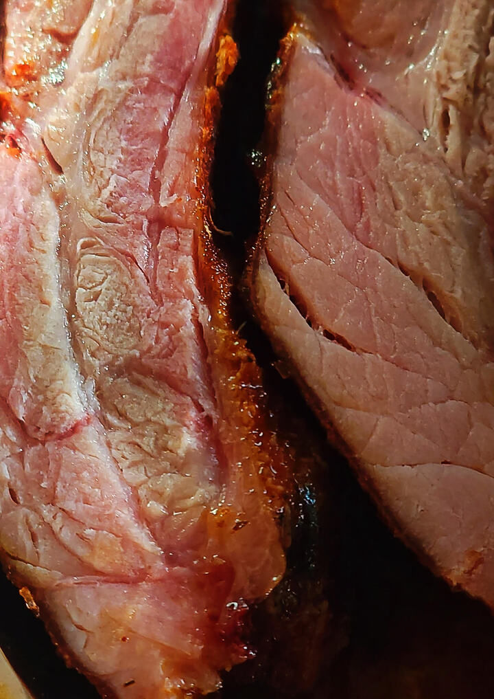 close up of finished barbecue baby back ribs, cut to show outside crust, pink smoke ring, and juicy meat