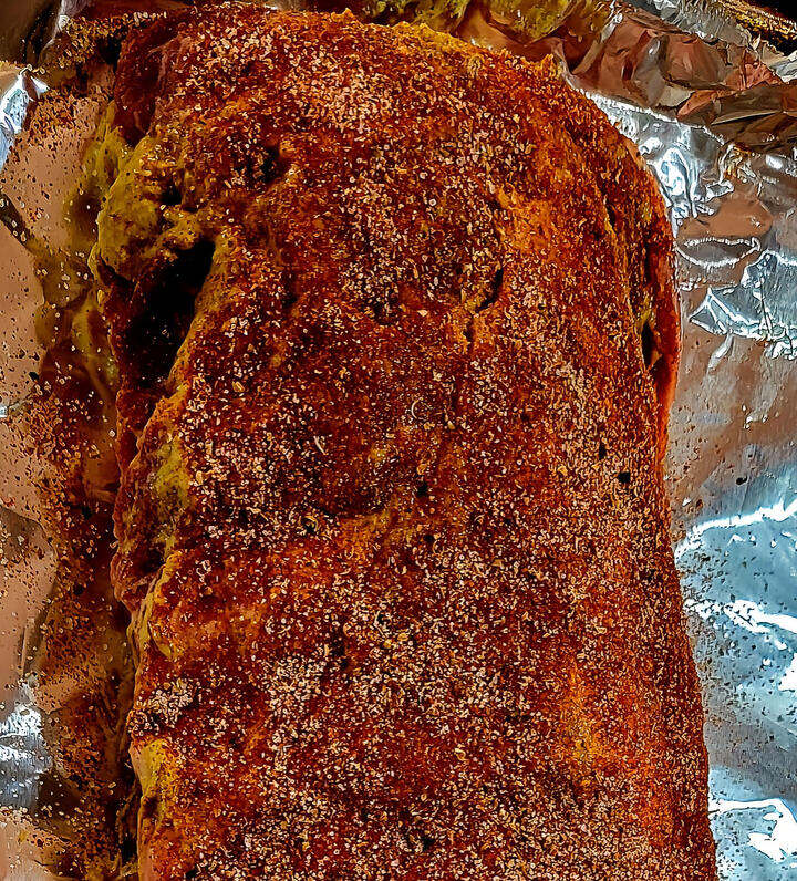 close up of baby back ribs rack, covered liberally with mustard and seasoning