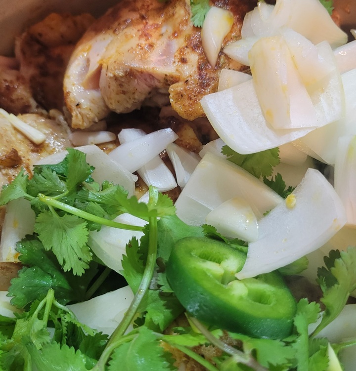close up of seared shicken thighs, yellow onion, jalapeno, and cilantro