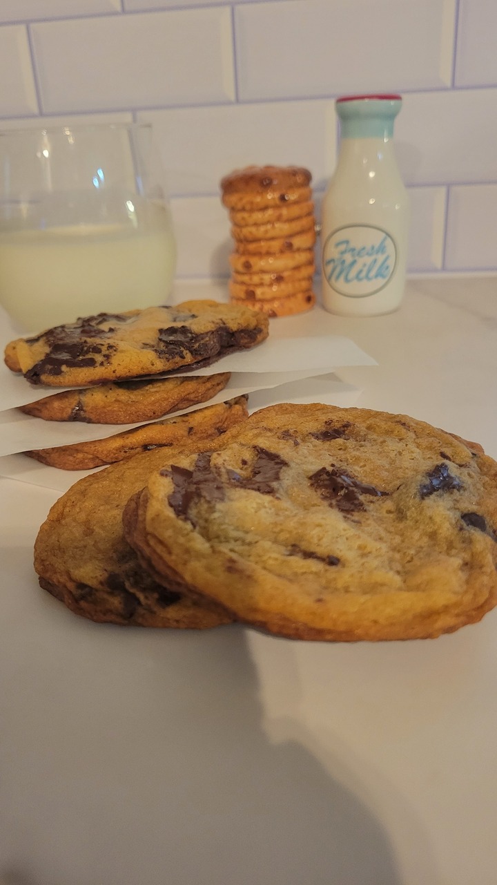 finished dark chocolate chunk cookies shown with cold glass of milk
