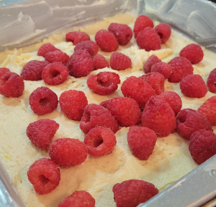 buttered pan with batter, topped with fresh raspberries