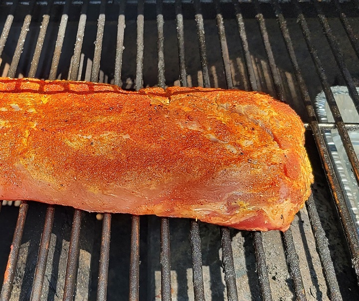 raw rack of ribs, coated in seasonings, on barbecue grill