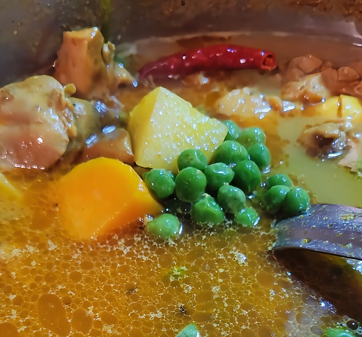 close up of chicken curry cooking with all ingredients added, not yet thickened