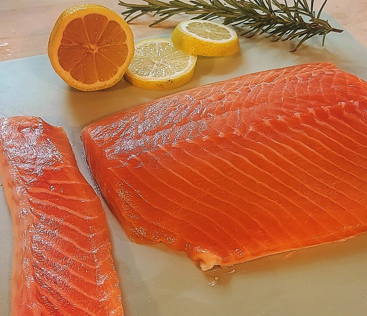 salmon filet, belly removed and set to one side, sliced lemon and rosemary in background