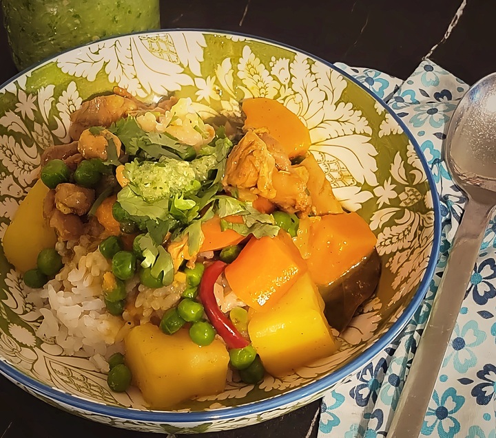 finished chicken curry over rice in bowl with spoon and spicy chutney