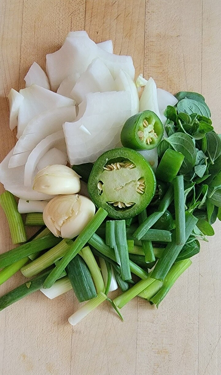 overhead shot of roughly chopped onion, jalapeno, oregano, garlic and green onion