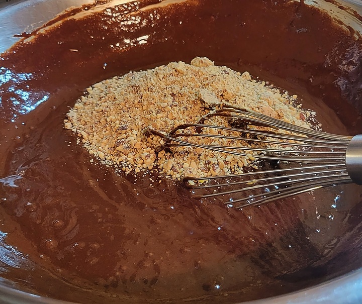 melted chocolate and chopped almonds on top in mixing bowl with wire whip