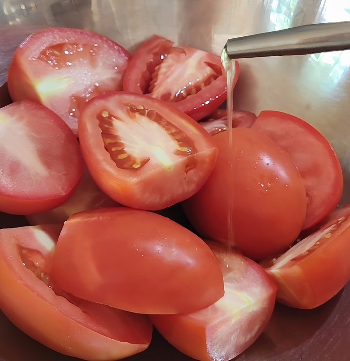 tomato halves being coated with olive oil