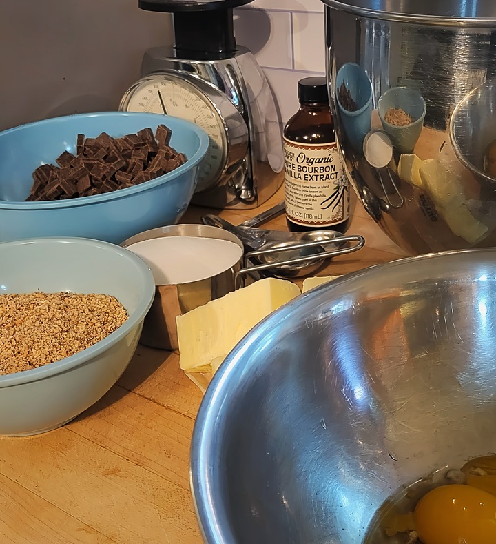 ingredients for flourless chocolate torte; eggs, butter, sugar, chopped almonds, dark chocolate, vanilla extract
