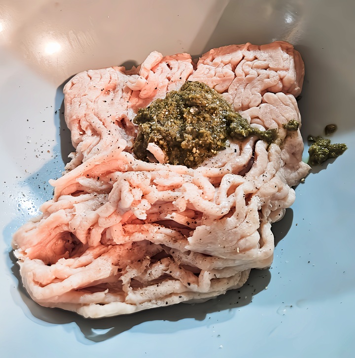 ground chicken in mixing bowl with pesto added