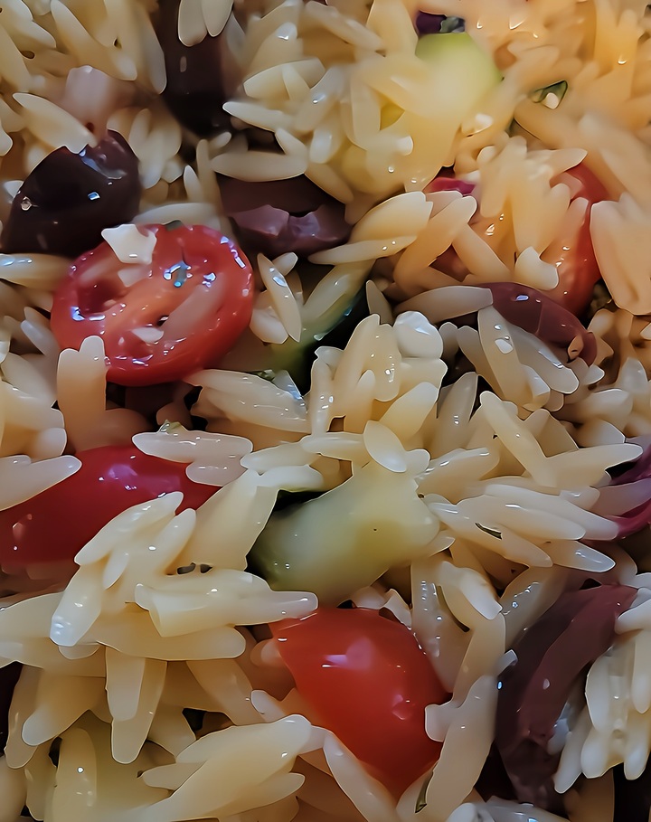 close up of finished Greek Orzo Pasta Salad, showing cucumber, tomato, olives, red onion, and orzo pasta