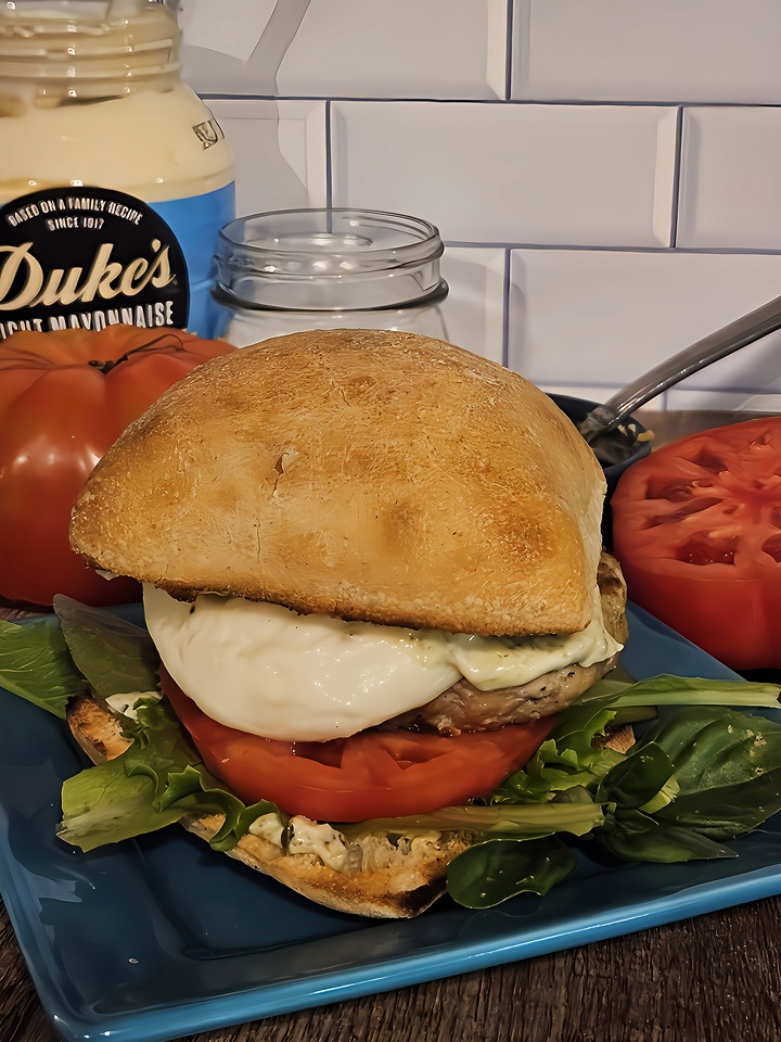 pesto chicken burger-chicken patty, fresh mozzarella, sliced tomato, fresh salad greens and basil in a toasted ciabatta bun.