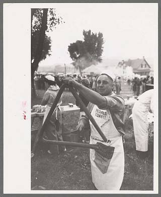 antique photo showing a cook ringing a triangle to call people to the barbecue